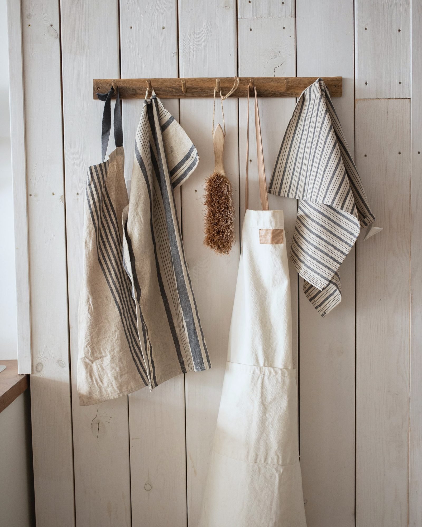 Aprons and striped towels hanging on a wooden peg rail